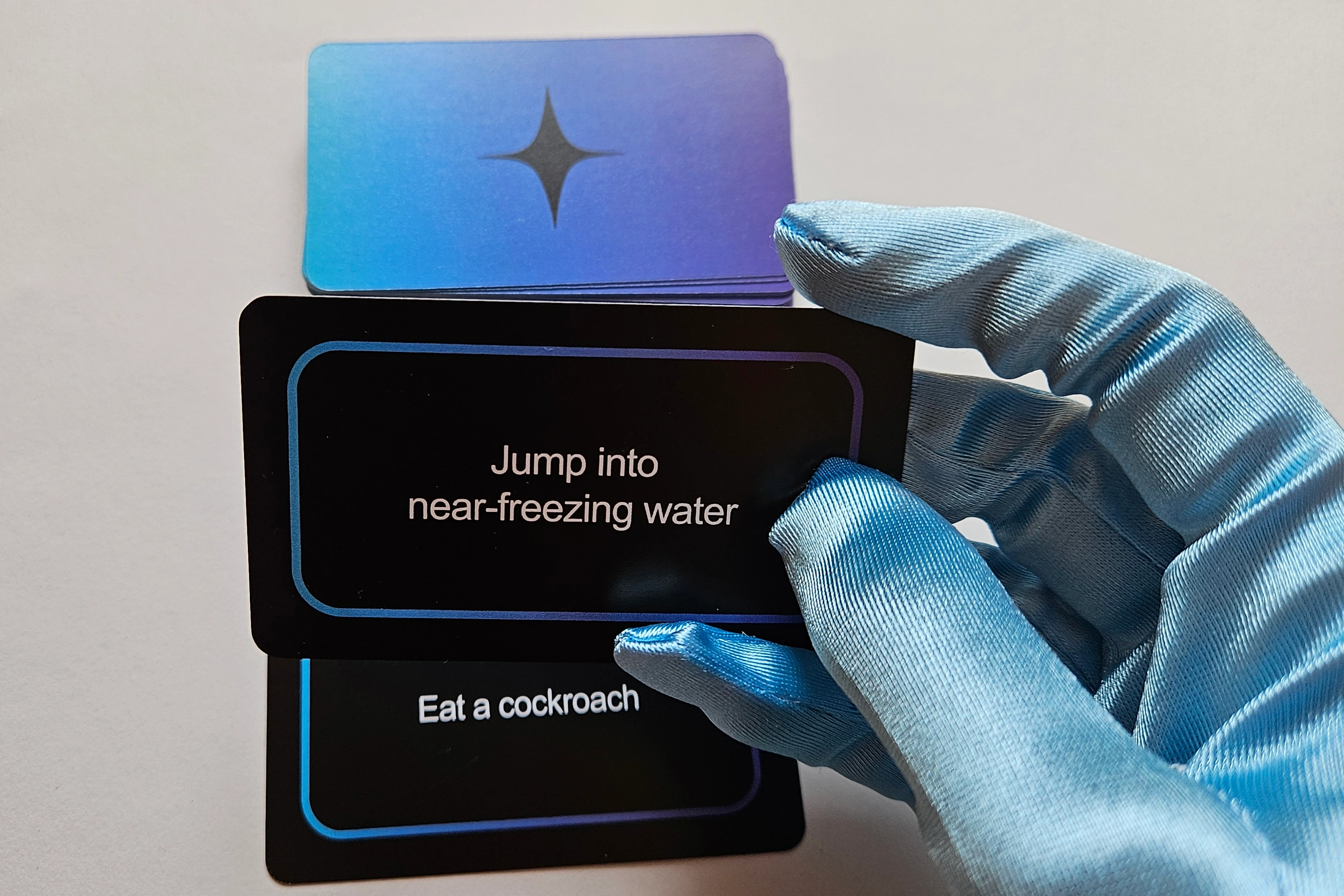 Gameplay photo of Deliberation card game with player holding a card, with the deck on table